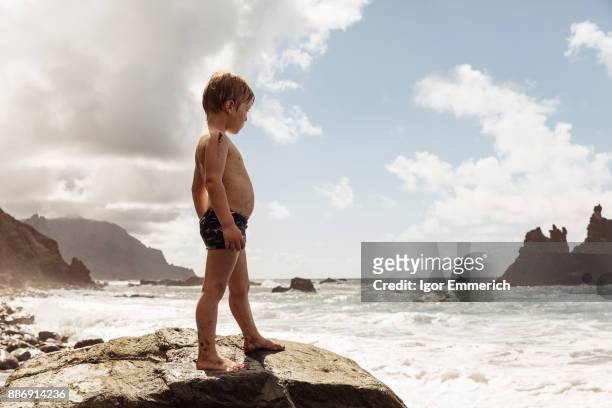 young boy standing on rock, looking at view, santa cruz de tenerife, canary islands, spain, europe - igor emmerich stock pictures, royalty-free photos & images