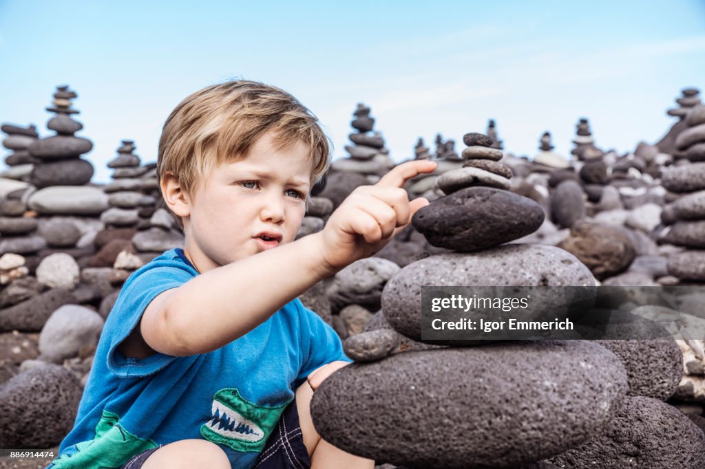 Young boy examining stack of rocks, Santa Cruz de Tenerife, Canary Islands, Spain, Europe