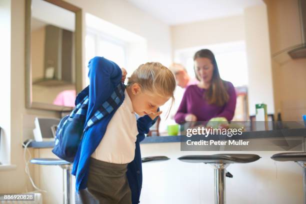 schoolgirl putting on school satchel in kitchen - enfant cartable photos et images de collection