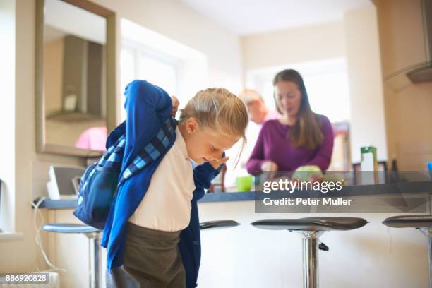 schoolgirl putting on school satchel in kitchen - satchel bag stock pictures, royalty-free photos & images