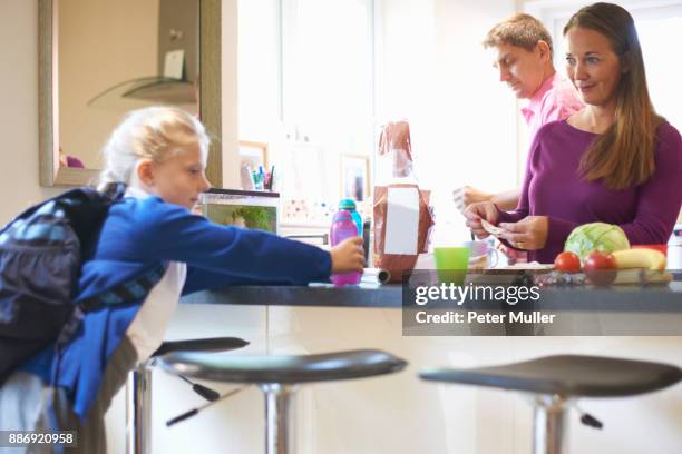 schoolgirl pick up drink from kitchen counter - school breakfast stock pictures, royalty-free photos & images