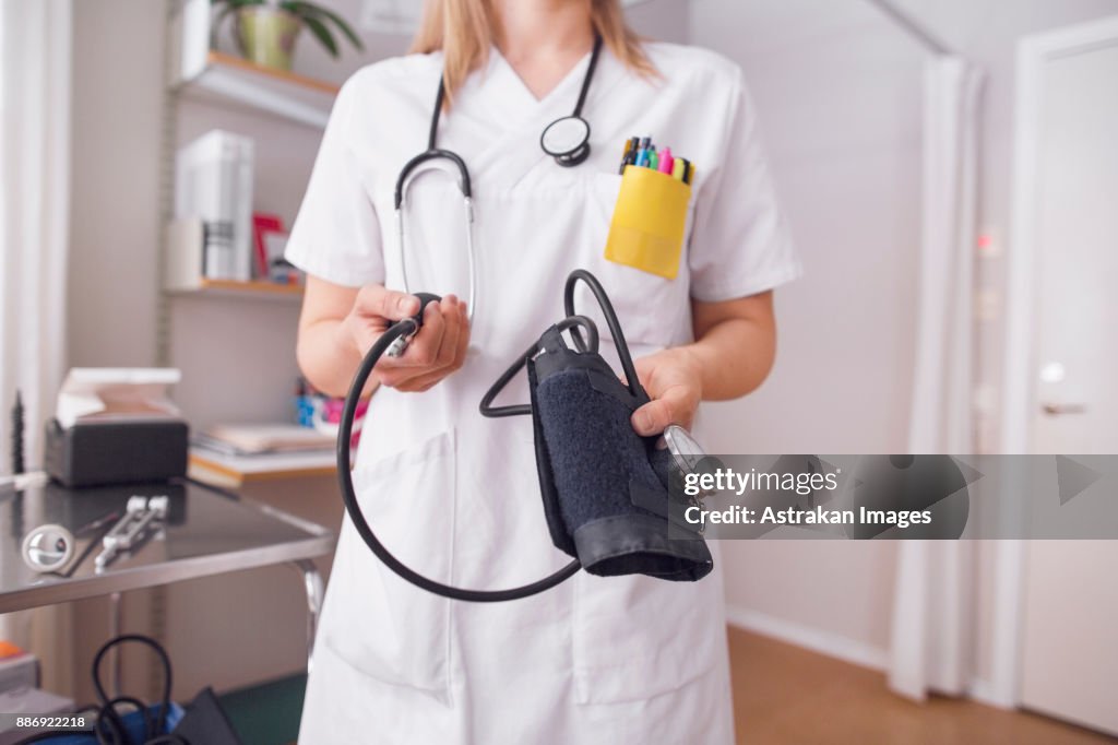 Young doctor in examination room holding blood pressure gauge