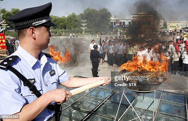 Chinese policeman lits a cauldron filled with illicit drugs during a ceremony to mark the UN's International Day Against Drug Abuse and Illicit...