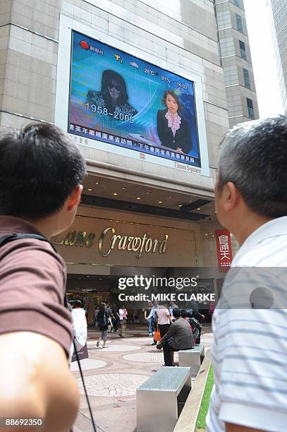 People watch a giant tv screen showing the news surrounding the death of singer Michael Jackson in Hong Kong on June 26, 2009. Michael Jackson died...
