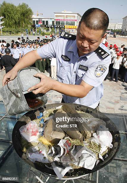 Chinese policeman pours a flammable liquid in a cauldron filled with illicit drugs during a ceremony to mark the UN's International Day Against Drug...