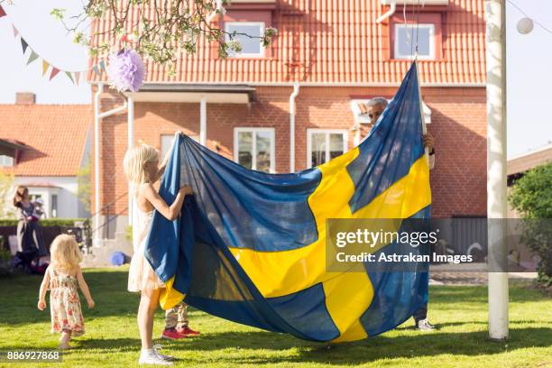 dad with daughters (18-23 months, 8-9) holding swedish flag - sweden flag stock-fotos und bilder