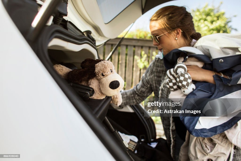 Woman packing clothes into car trunk