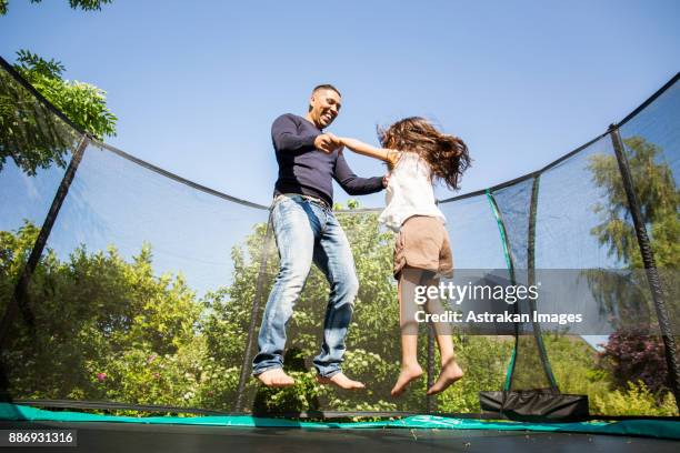 girl (6-7) jumping on trampoline with father - trampoline jump stock pictures, royalty-free photos & images