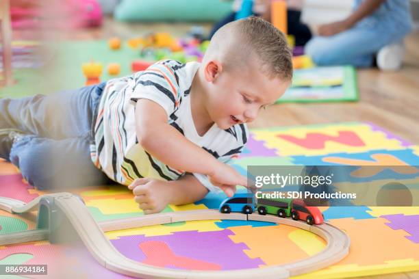 little boy moves toy train along its track - differential focus stock pictures, royalty-free photos & images