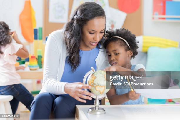 child care worker answers little girl's questions about a globe - 1 earth productions stock pictures, royalty-free photos & images