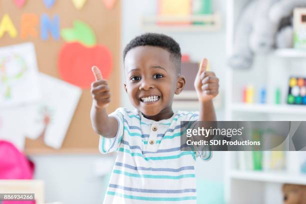 adorable boy gives thumbs up in preschool - boa imagens e fotografias de stock