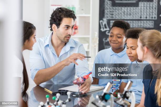 confident indian male science teacher works with group of students - private school uniform stock pictures, royalty-free photos & images