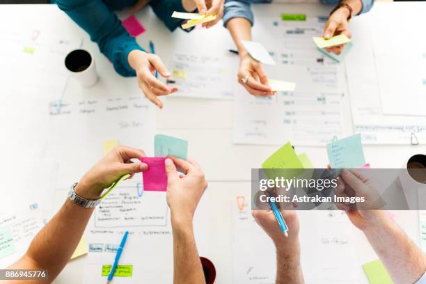 colleagues using adhesive notes during business meeting - postit stockfoto's en -beelden