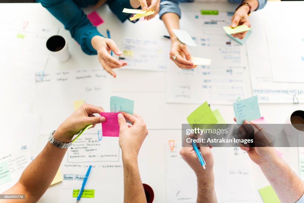 Colleagues using adhesive notes during business meeting