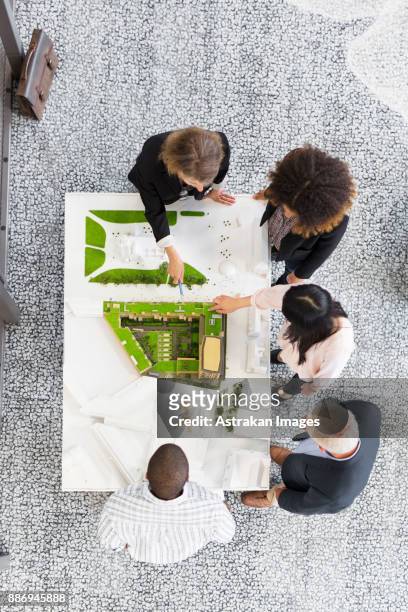 overhead view of architects discussing blueprint - architekturmodell stock-fotos und bilder