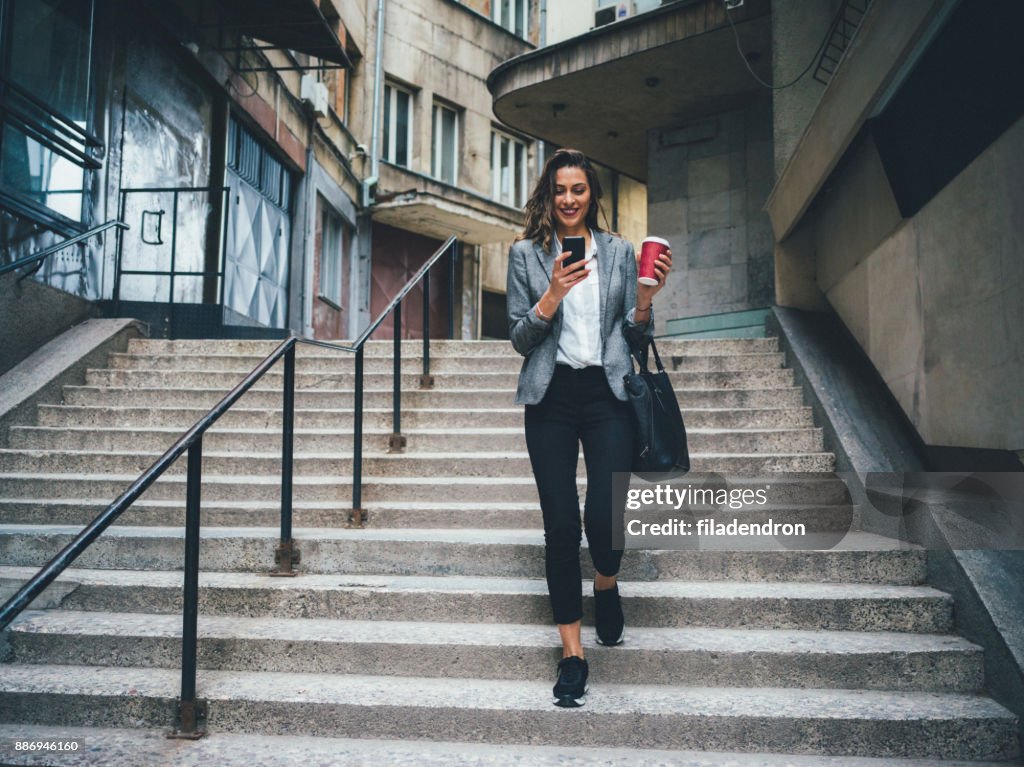 Woman texting and drinking coffee outdoors