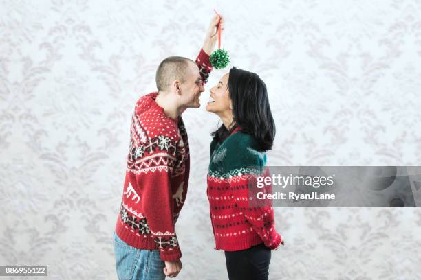 christmas sweater couple kiss under mistletoe - ugly asian woman stock pictures, royalty-free photos & images