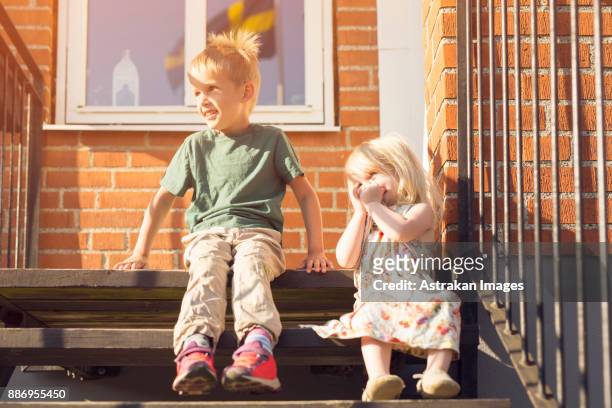 boy (4-5) and girl (18-23 months) sitting on stairs outdoors - 2 5 months 個照片及圖片檔