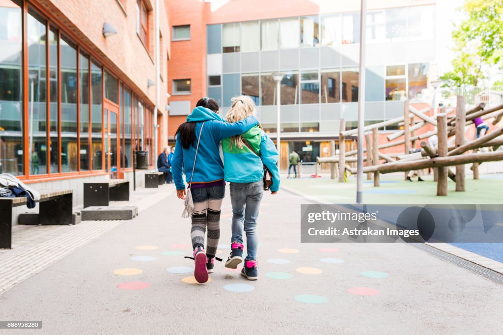 Girls (8-9) embracing and walking together