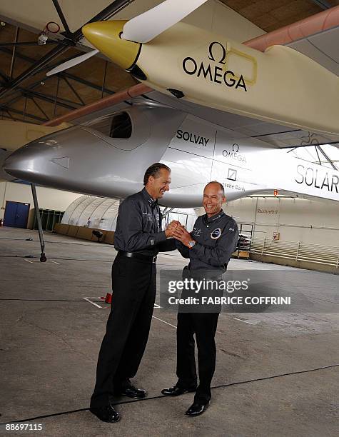Swiss scientist-adventurer and pilot Bertrand Piccard and Solar Impulse CEO Andre Borschberg pose under the 'Solar Impulse' airplane after an...
