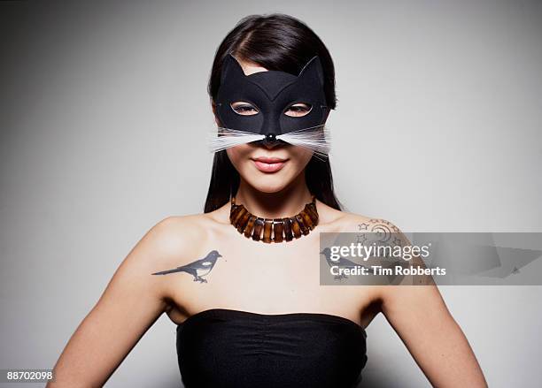 young woman with cat mask and bird tattoos - maskiert stock-fotos und bilder