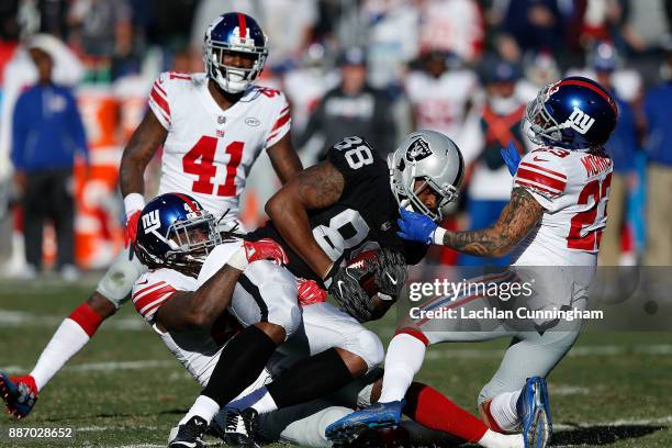 Clive Walford of the Oakland Raiders is tackled by Kelvin Sheppard and Darryl Morris of the New York Giants at Oakland-Alameda County Coliseum on...