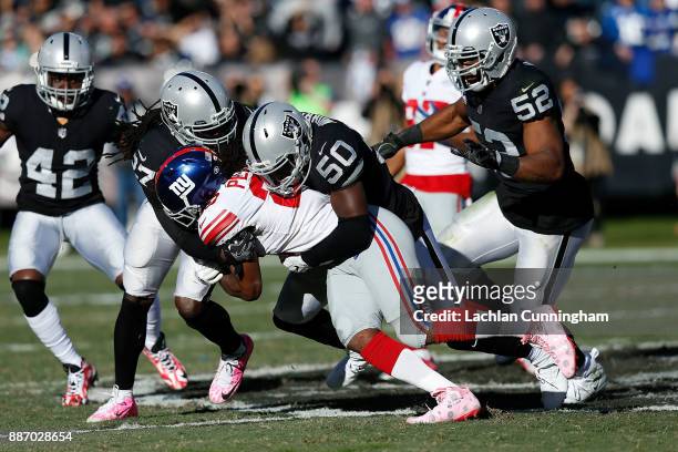 Paul Perkins of the New York Giants is tackled by Reggie Nelson and Nicholas Morrow of the Oakland Raiders at Oakland-Alameda County Coliseum on...