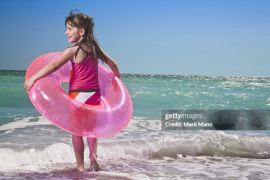 Young girls standing in the saves with inner tube.