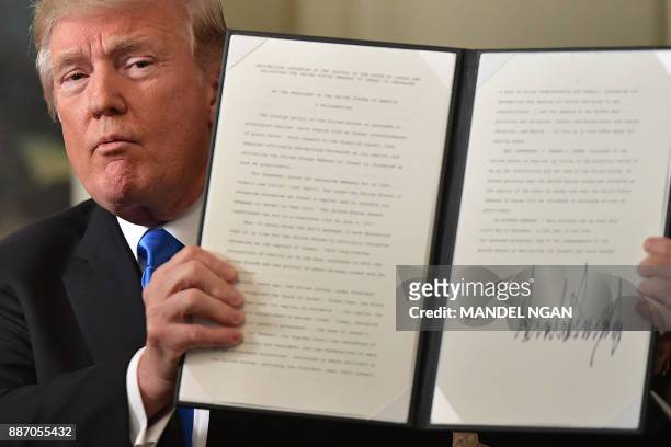 President Donald Trump holds up a signed proclamation after he delivered a statement on Jerusalem from the Diplomatic Reception Room of the White...