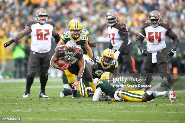 Charles Sims of the Tampa Bay Buccaneers is tripped up by Ha Ha Clinton-Dix of the Green Bay Packers during a game at Lambeau Field on December 3,...