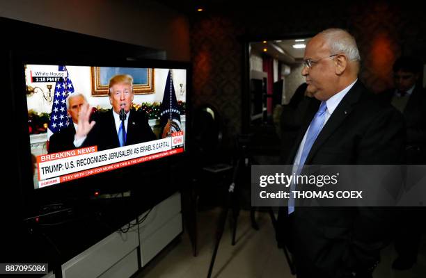 Chief Palestinian negotiator Saeb Erekat watches on TV a speech given by US President Donald Trump at his residence in the West Bank city of Jericho,...