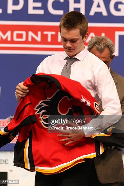 Tim Erixon puts on his Calgary Flames sweater after he was selected overall by the Flames during the first round of the 2009 NHL Entry Draft at the...