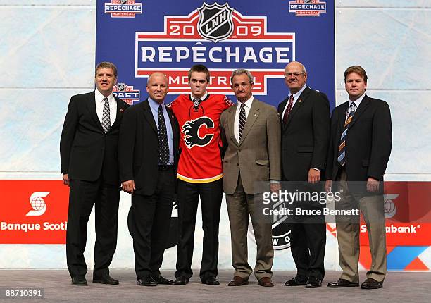 Tim Erixon of the Calgary Flames poses on stage with members the Flames organization after Erixon was selected overall by the Flames during the first...