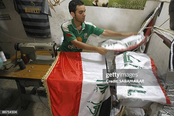 An Iraqi man sits at a sewing machine as he assembles an Iraqi flag at his shop in central Baghdad on June 27, 2009. The flag maker says he is busy...