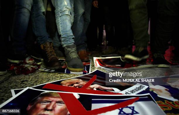 Palestinian demonstrators stand on posters of the US president in Bethlehem's Manger Square in protest to him declaring Jerusalem as Israel's capital...