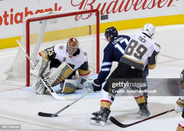 Goaltender Maxime Lagace of the Vegas Golden Knights guards the net as Adam Lowry of the Winnipeg Jets drives the puck towards the goal during third...