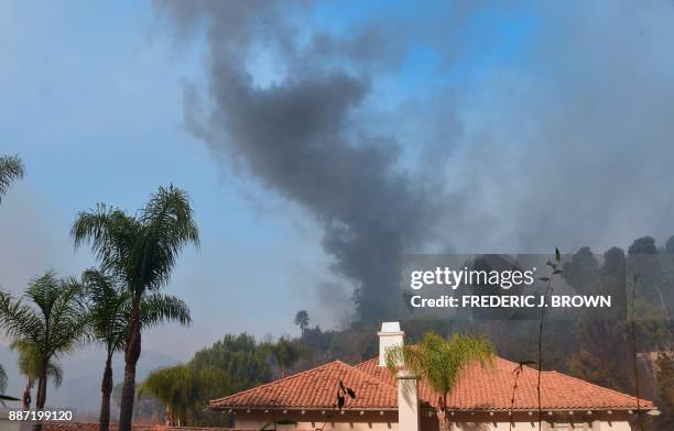 Huge plume of black smoke rises from a burning home behind one still standing on a hilltop in Bel Air, east of the 405 freeway on December 6, 2017 in...