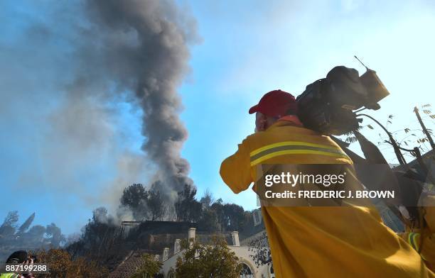 Members of the media document the scene of burning homes in Bel Air on December 6, 2017 in Los Angeles, California. California motorists commuted...