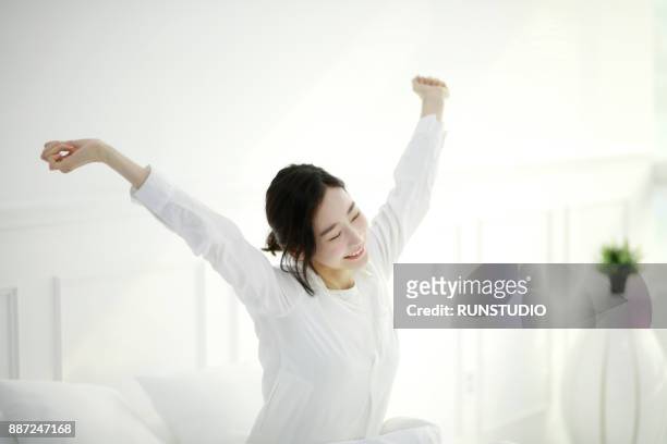 young woman smiling and stretching in bed - good morning ストックフォトと画像