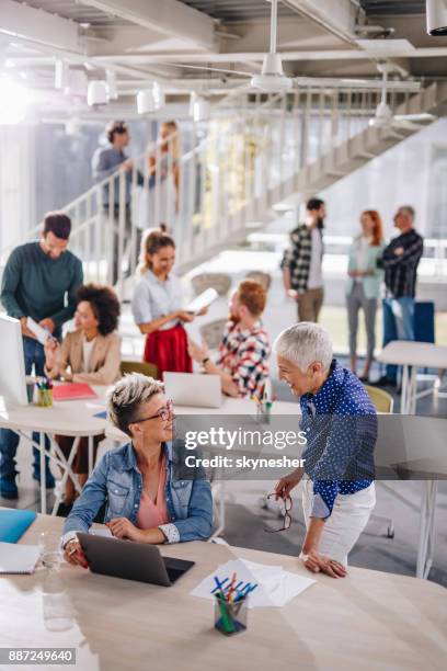 happy businesswomen talking to each other in corporate office full of people. - creative crowd imagens e fotografias de stock