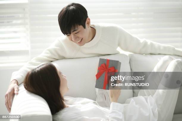 happy couple with gift box in living room - gift japan photos et images de collection