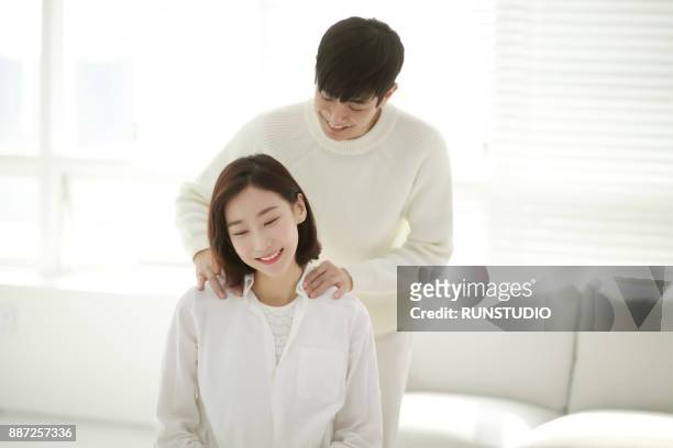 man massaging  woman shoulder in living room - girlfriend massage stock pictures, royalty-free photos & images