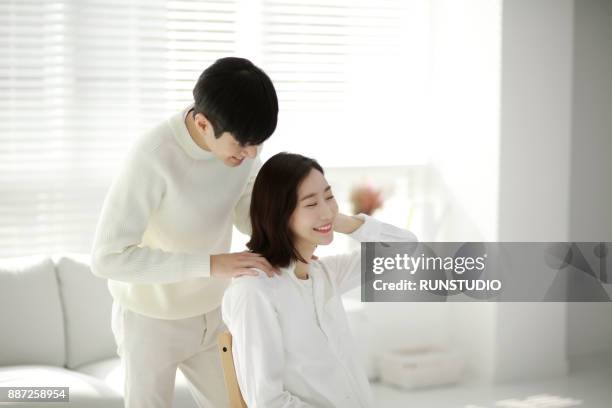 man giving massage woman's shoulder in living room - girlfriend massage stock pictures, royalty-free photos & images