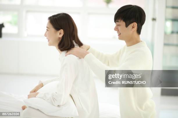 man massaging  woman shoulder in living room - girlfriend massage stock pictures, royalty-free photos & images