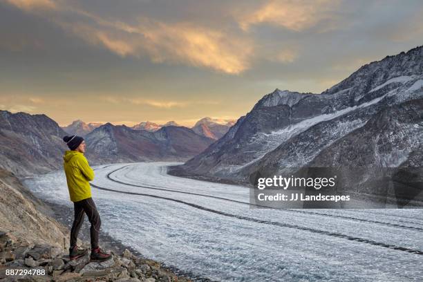male hiker watching sunset over glacier and mountains, aletsch glacier, switzerland - aletsch glacier stock pictures, royalty-free photos & images