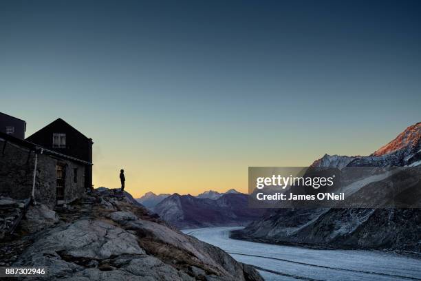 hiker silhouette watching sunrise over mountain range and glacier, aletsch glacier, switzerland - european landscapes stock-fotos und bilder