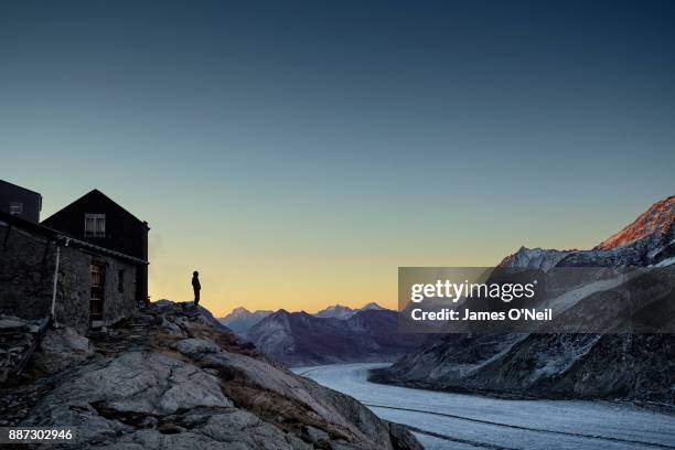 hiker silhouette watching sunrise over mountain range and glacier, aletsch glacier, switzerland - chalet mountain foto e immagini stock