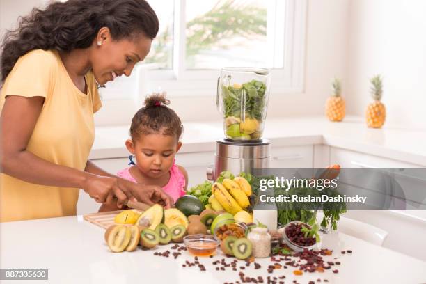 mother with 2-3 years old daughter cutting fruits in the kitchen. - mint plant family stock pictures, royalty-free photos & images