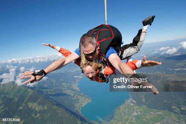 this couple are doing a tandem skydiving jump over a beautiful lake and mountain scenery. - northern european descent ストックフォトと画像