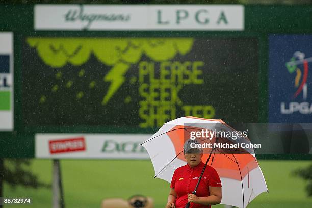 Jiyai Shin of South Korea waits to play in heavy rain on the 18th green during the final round of the Wegmans LPGA at Locust Hill Country Club held...